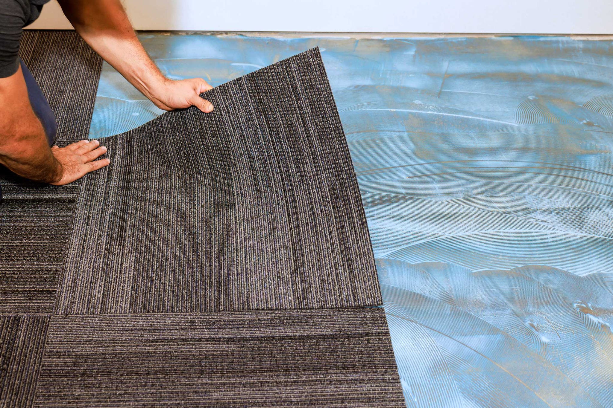 Commercial carpet tile being installed over prepared adhesive